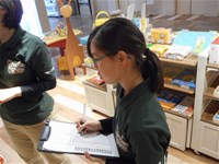 何かを見ながらクリップボードにメモを取る生徒