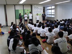 体育館で実行委員長の話を聞く生徒たち